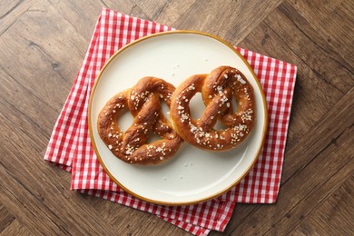 Photo of Tasty pretzels with salt on wooden table, top view
