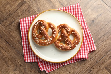 Photo of Tasty pretzels with salt on wooden table, top view