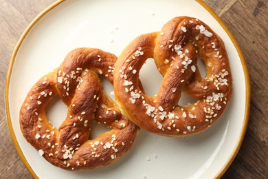 Photo of Tasty pretzels with salt on wooden table, top view