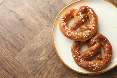Photo of Tasty pretzels with salt on wooden table, top view. Space for text