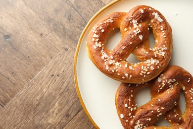 Photo of Tasty pretzels with salt on wooden table, top view. Space for text