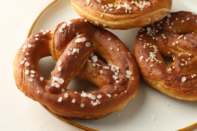 Photo of Tasty pretzels with salt on white table, closeup