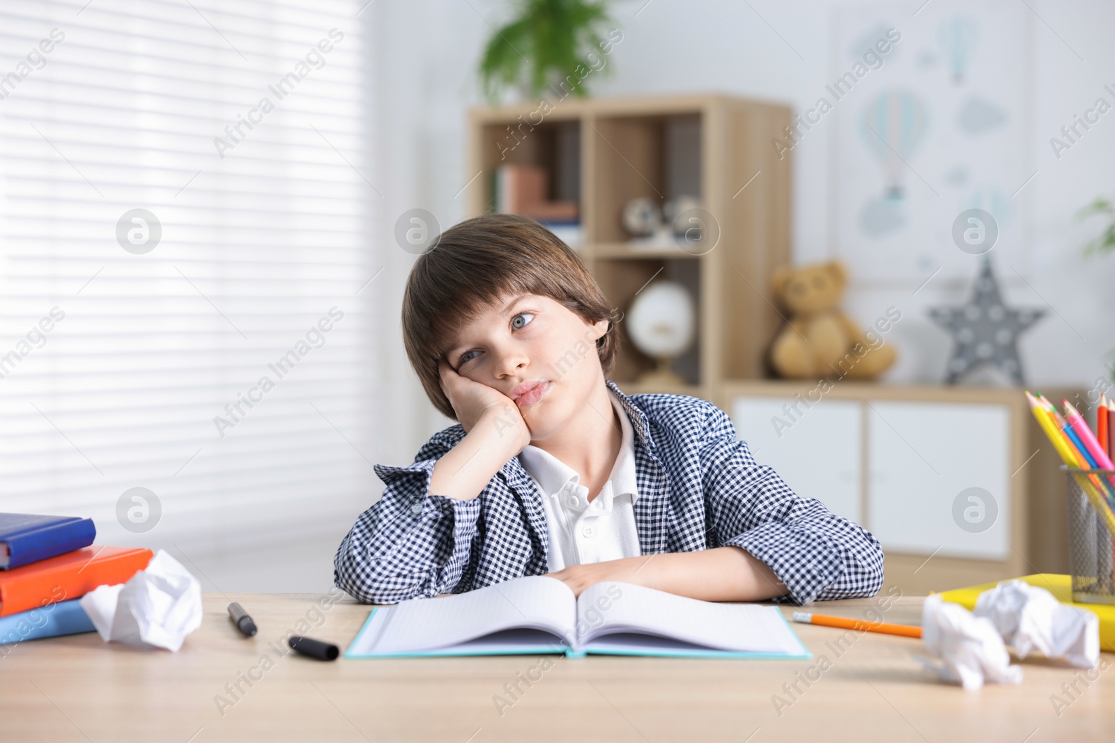 Tired little boy doing homework at table indoors Photo of Tired little boy doing homework at table indoors