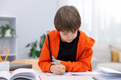 Photo of Cute little boy doing homework at desk indoors