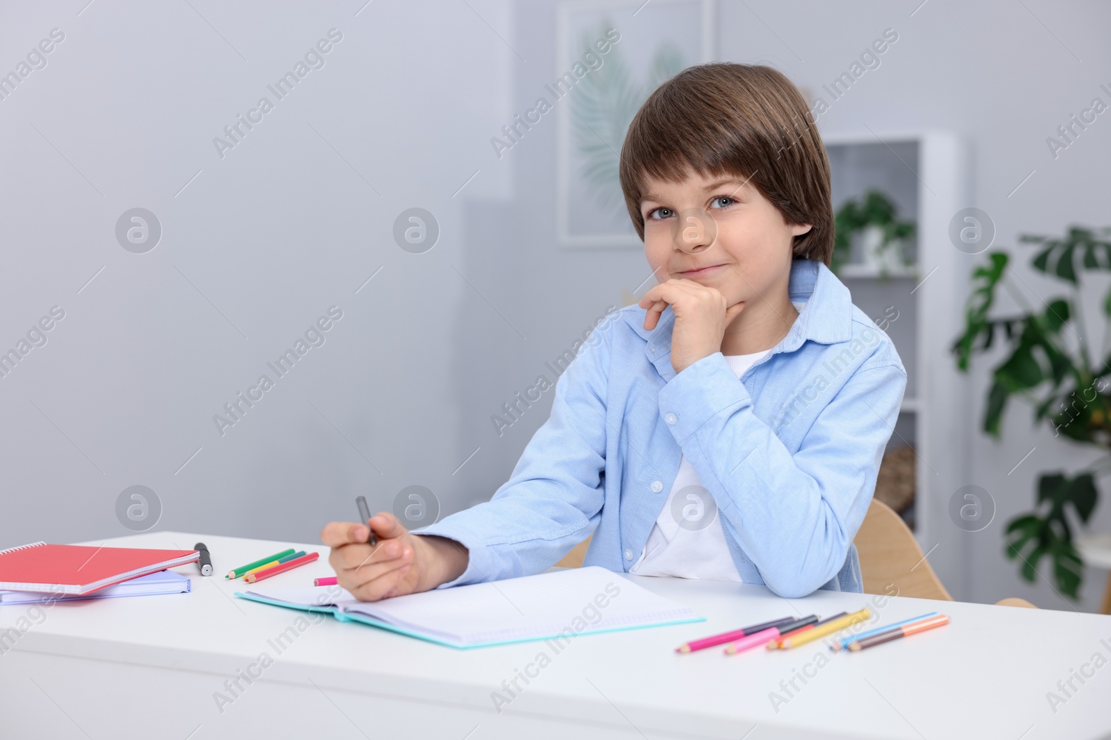 Cute little boy doing homework at table indoors Photo of Cute little boy doing homework at table indoors