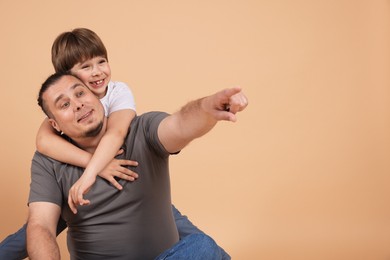 Photo of Father and his son on beige background, space for text