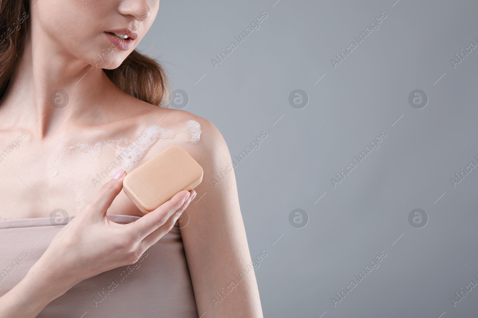 Woman with soap bar on grey background, closeup. Space for text Photo of Woman with soap bar on grey background, closeup. Space for text