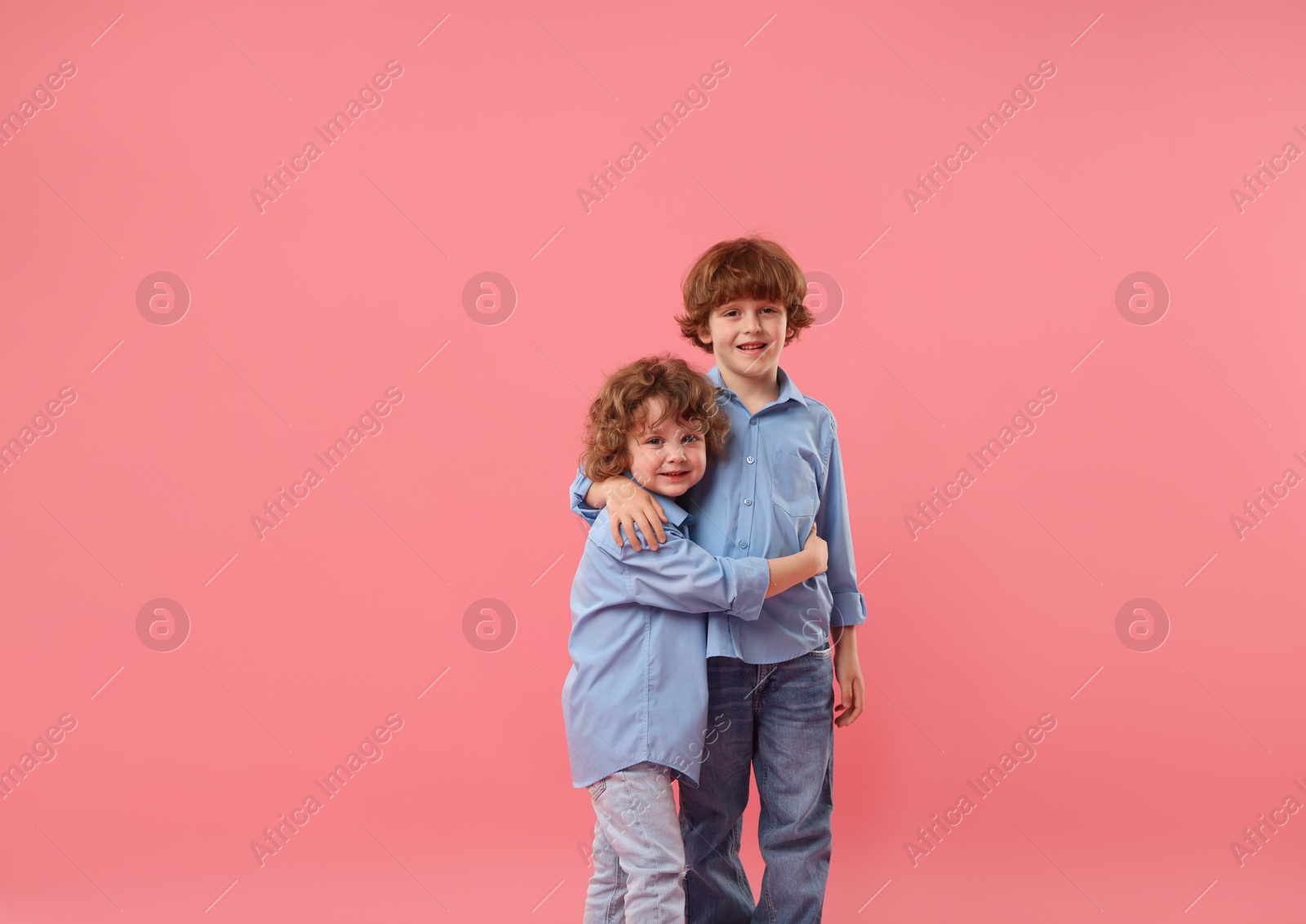 Cute little brothers hugging on pink background Photo of Cute little brothers hugging on pink background