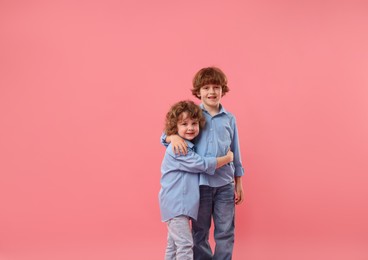 Photo of Cute little brothers hugging on pink background
