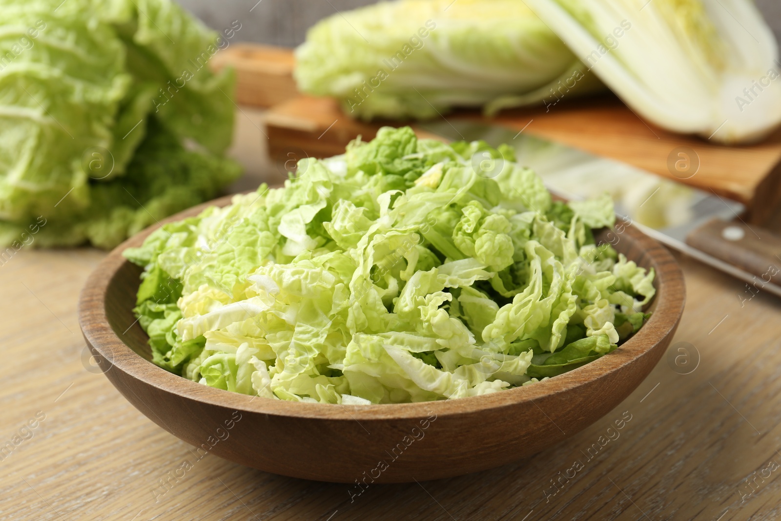 Fresh Chinese cabbages and knife on wooden table, closeup Photo of Fresh Chinese cabbages and knife on wooden table, closeup