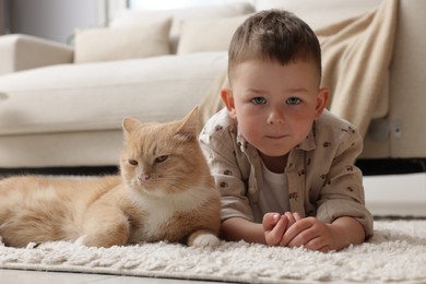 Photo of Little boy with his cute ginger cat at home