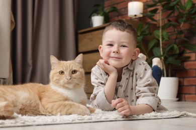 Photo of Little boy with his cute ginger cat at home
