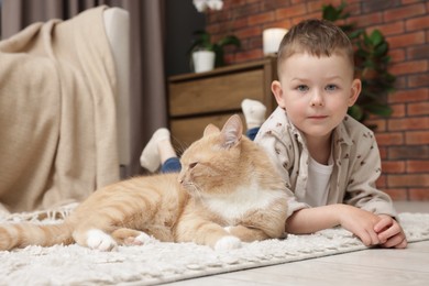 Photo of Little boy with his cute ginger cat at home