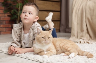 Photo of Little boy with his cute ginger cat at home