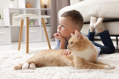 Photo of Little boy with his cute ginger cat at home