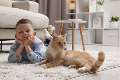 Photo of Little boy with his cute ginger cat at home