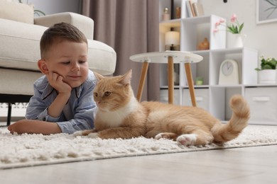 Photo of Little boy with his cute ginger cat at home
