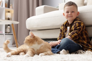 Photo of Little boy with his cute ginger cat at home