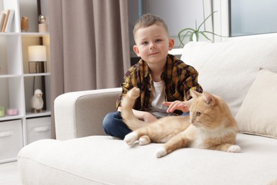 Photo of Little boy with his cute ginger cat at home