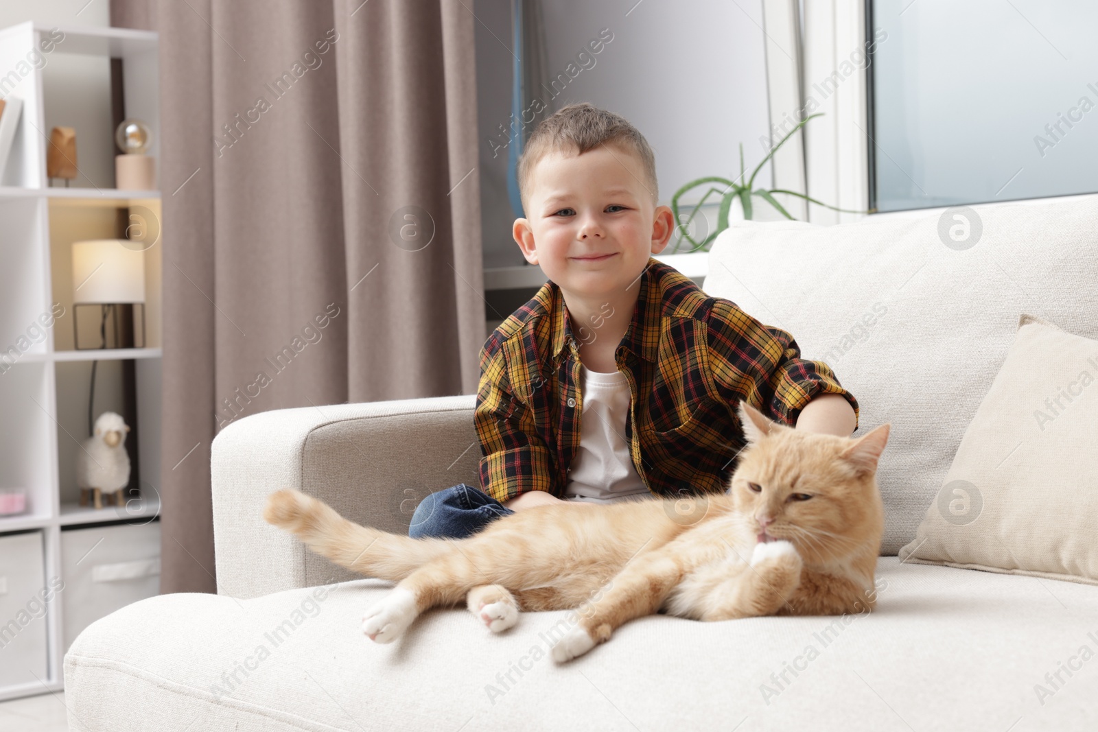 Little boy with his cute ginger cat at home Photo of Little boy with his cute ginger cat at home