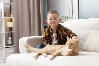 Photo of Little boy with his cute ginger cat at home