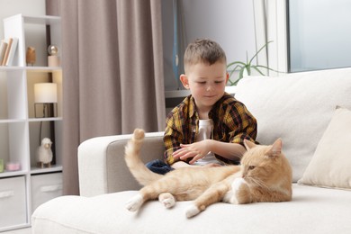 Photo of Little boy with his cute ginger cat at home