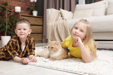 Photo of Little kids with their cute ginger cat at home