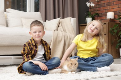 Photo of Little kids with their cute ginger cat at home