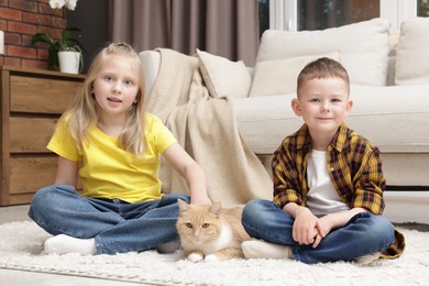 Photo of Little kids with their cute ginger cat at home