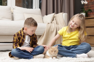 Photo of Little kids with their cute ginger cat at home