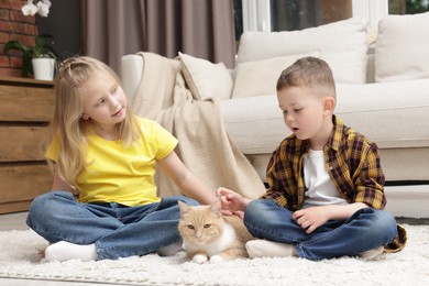 Photo of Little kids with their cute ginger cat at home