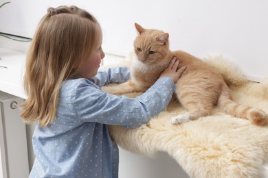 Photo of Little girl with her cute ginger cat at home