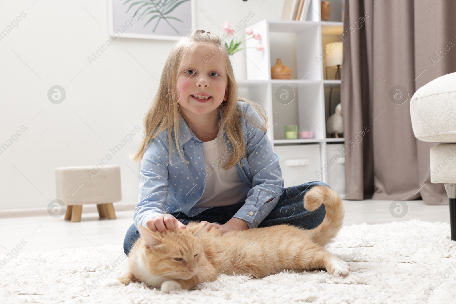 Little girl with her cute ginger cat at home Photo of Little girl with her cute ginger cat at home
