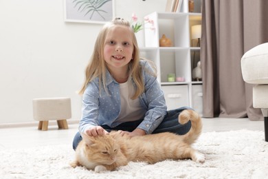 Photo of Little girl with her cute ginger cat at home
