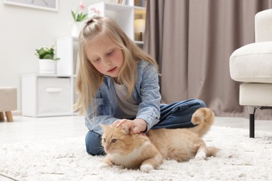 Photo of Little girl with her cute ginger cat at home