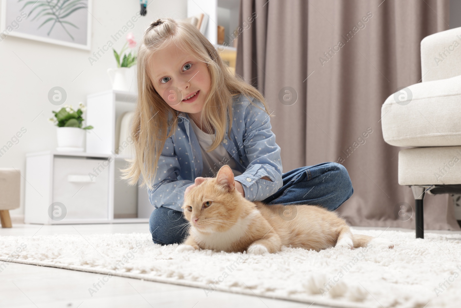 Photo of Little girl with her cute ginger cat at home