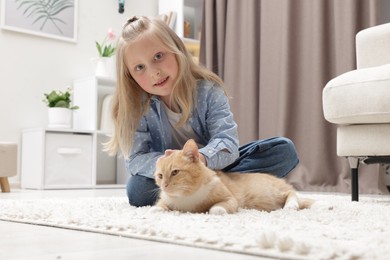 Photo of Little girl with her cute ginger cat at home