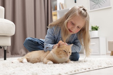 Photo of Little girl with her cute ginger cat at home