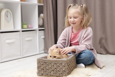 Photo of Little girl with her cute ginger cat at home, space for text