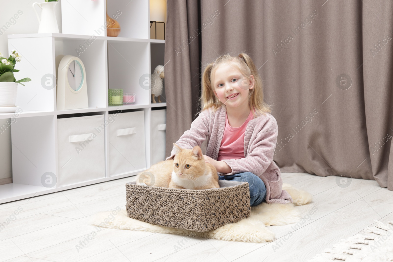 Little girl with her cute ginger cat at home Photo of Little girl with her cute ginger cat at home