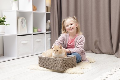 Photo of Little girl with her cute ginger cat at home