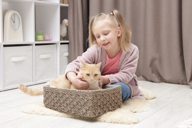 Photo of Little girl with her cute ginger cat at home