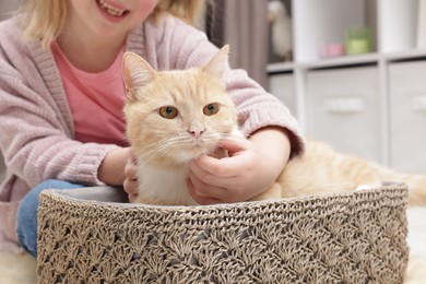 Photo of Little girl with her cute ginger cat at home, closeup