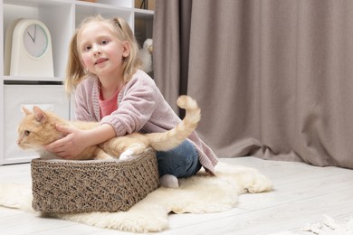Photo of Little girl with her cute ginger cat at home, space for text