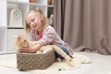 Photo of Little girl with her cute ginger cat at home, space for text