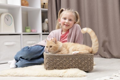 Photo of Little girl with her cute ginger cat at home
