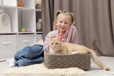 Photo of Little girl with her cute ginger cat at home