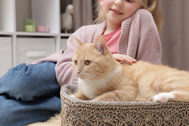 Photo of Little girl with her cute ginger cat at home, closeup