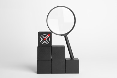 Image of Targeting. Stacked cubes with bullseye and magnifying glass on light background