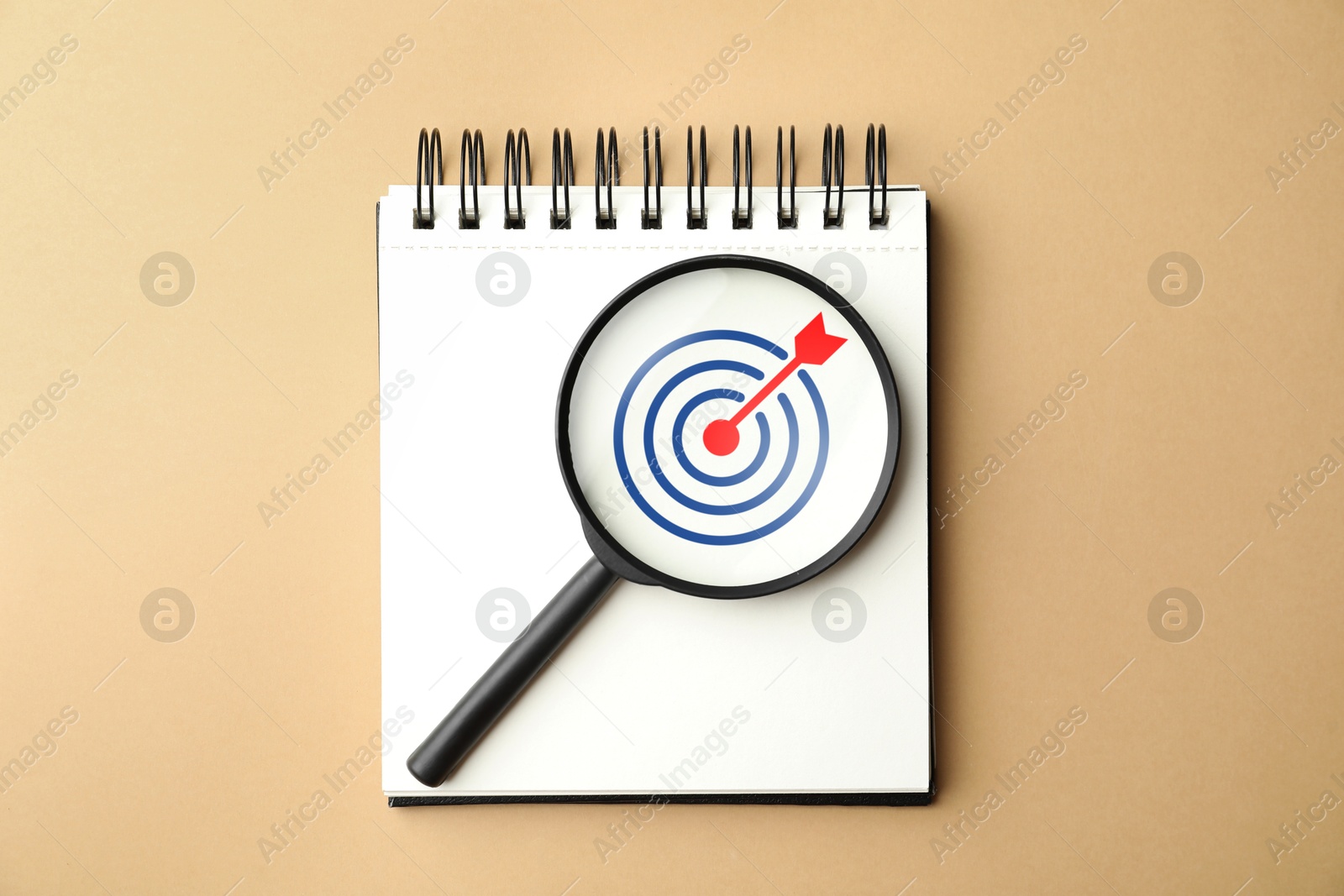 Targeting. Notebook with bullseye and magnifying glass on dark beige background, top view Image of Targeting. Notebook with bullseye and magnifying glass on dark beige background, top view